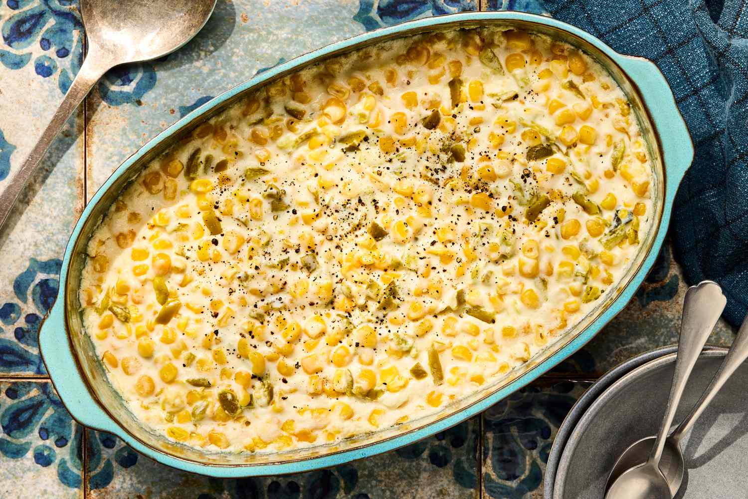 A glass meal prep container filled with leftover creamy corn, covered with a lid on a kitchen counter next to a spoon