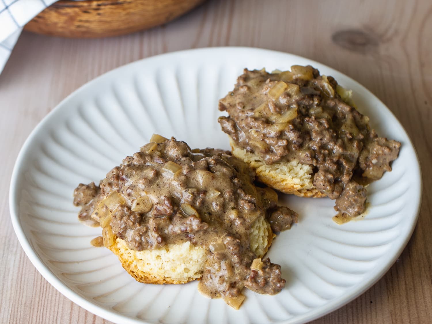 A glass meal prep container filled with leftover hamburger beef gravy with the lid set beside it