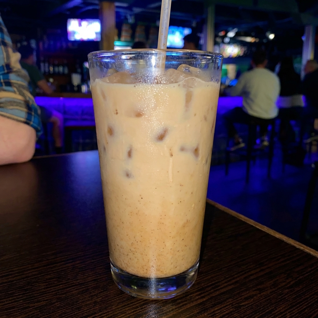 A glass of iced chai latte on a wooden table
