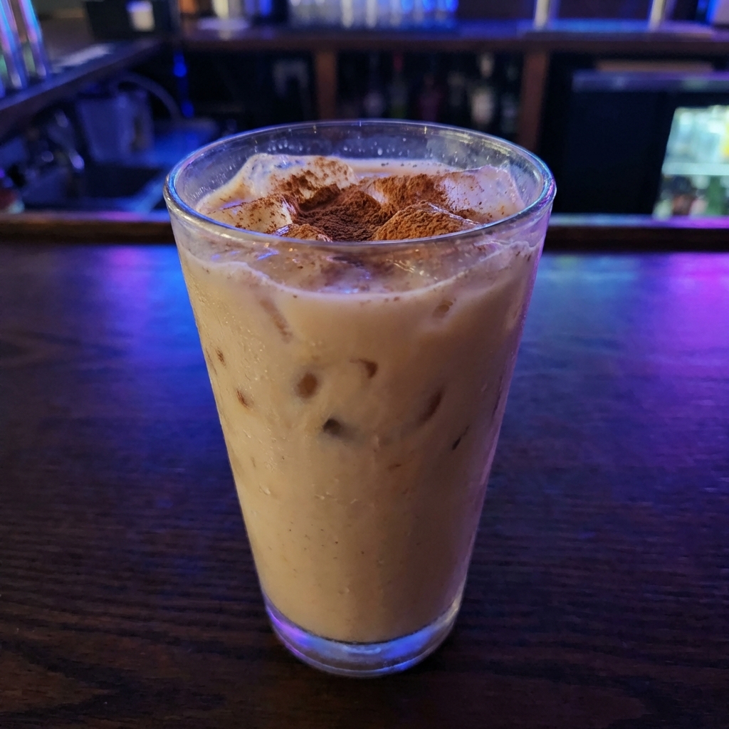 A glass of iced chai tea with cinnamon sprinkled on top