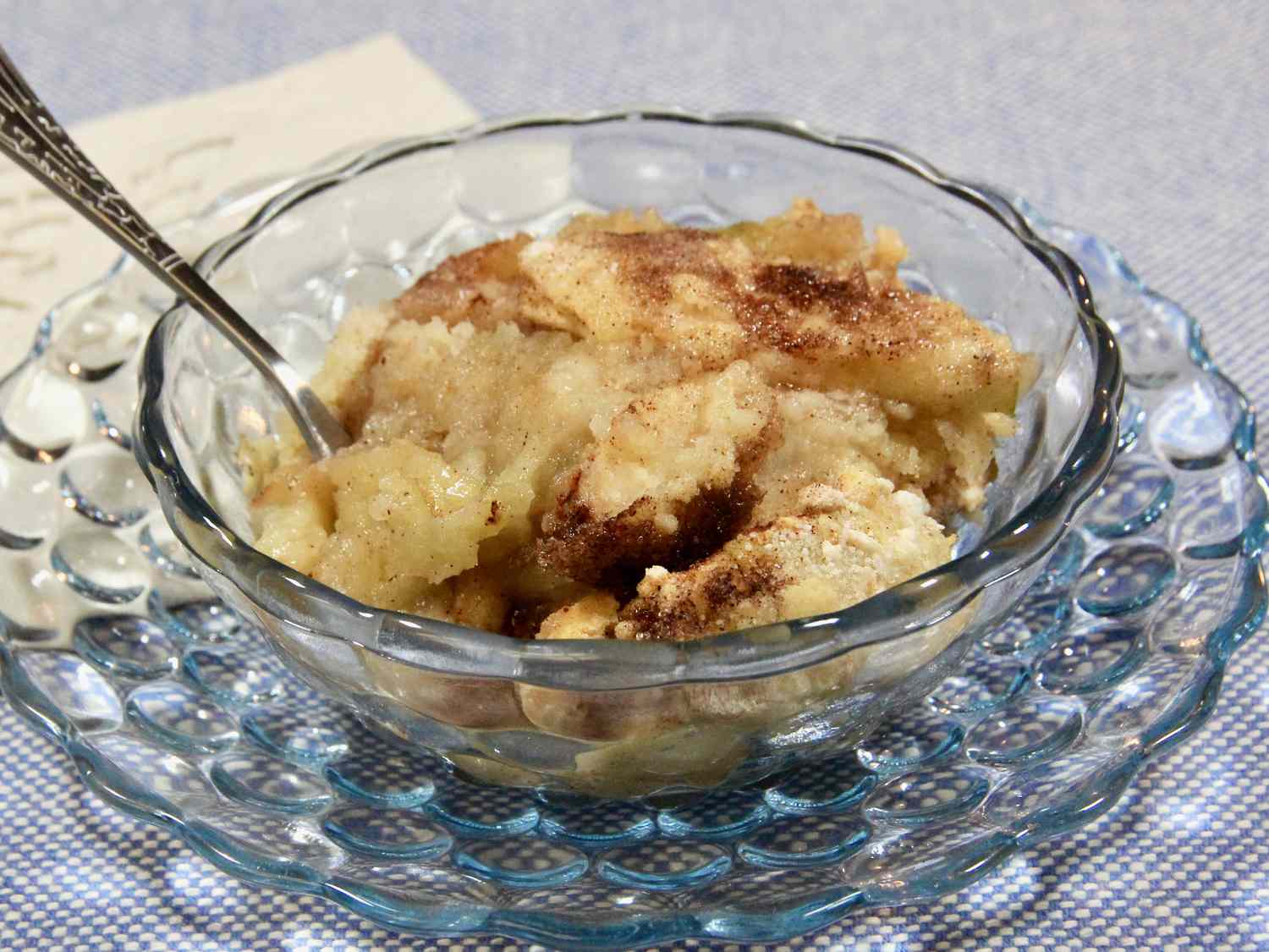 A golden apple crisp without oats in a glass baking dish, with bubbling cinnamon apples and a crisp brown sugar topping on a cozy kitchen counter