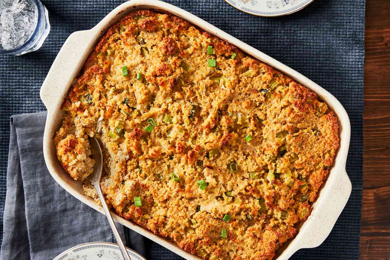 A golden baked pan of cornbread dressing in a casserole dish with crisp browned edges on a wooden table