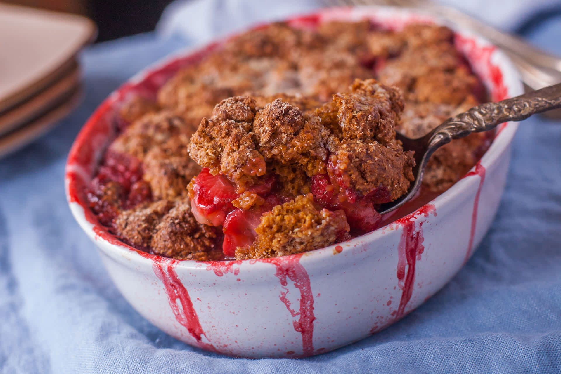A golden strawberry cobbler with bubbling red strawberry filling and a rustic biscuit topping on a warm kitchen counter
