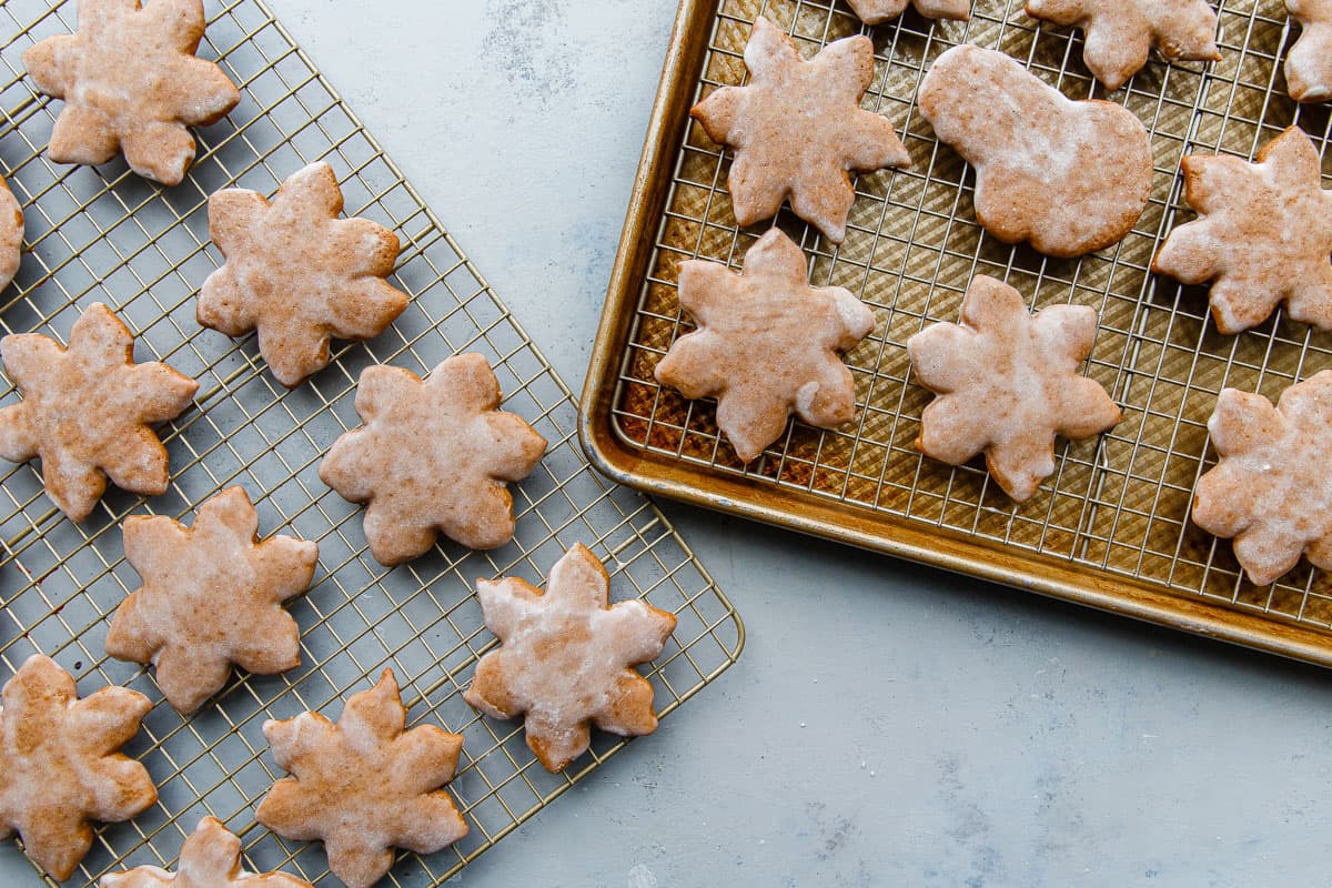 A hand using a pastry brush to glaze freshly baked lebkuchen cookies on a wire rack, with a small bowl of glaze on the counter
