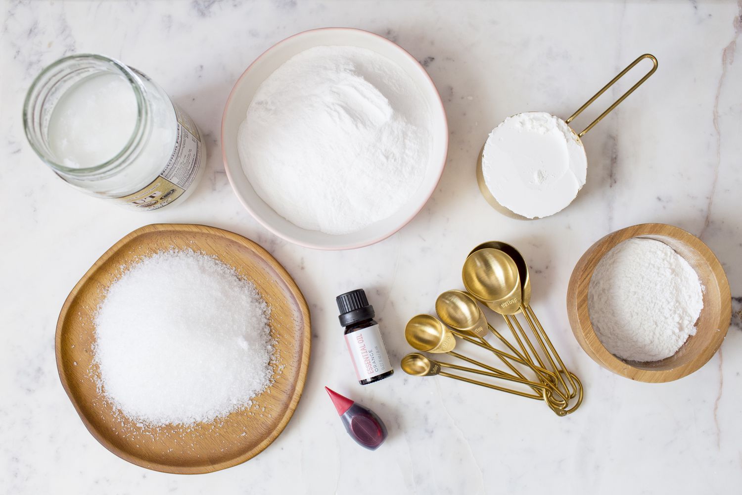 A hand whisking baking soda and citric acid together in a large glass bowl on a bright kitchen counter