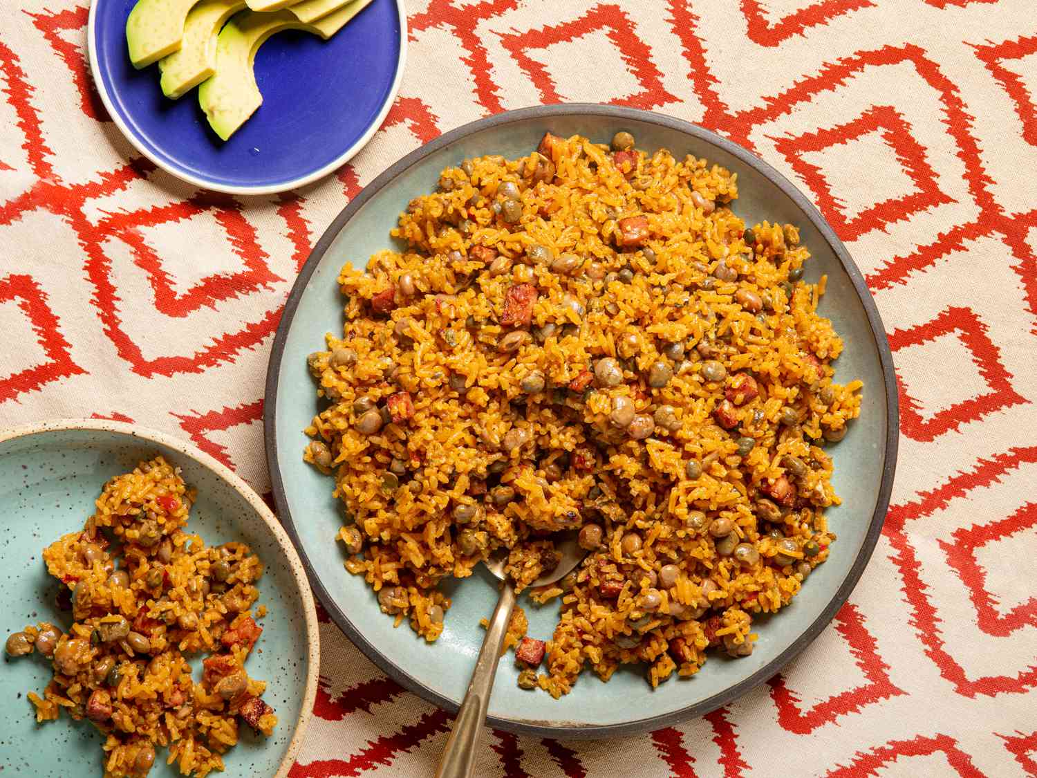A heaping serving of Puerto Rican arroz con gandules on a white plate, with golden rice, pigeon peas, and a few crispy browned bits, set on a warm-toned kitchen table
