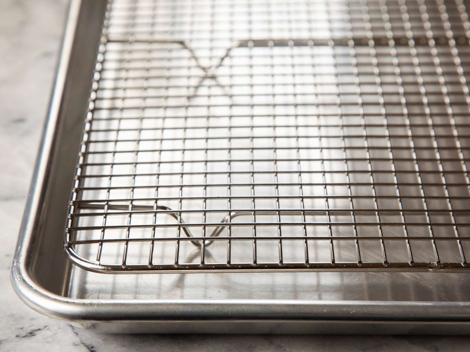 A heavy pot of oil on a stovetop next to a sheet pan lined with a wire rack for draining fried food