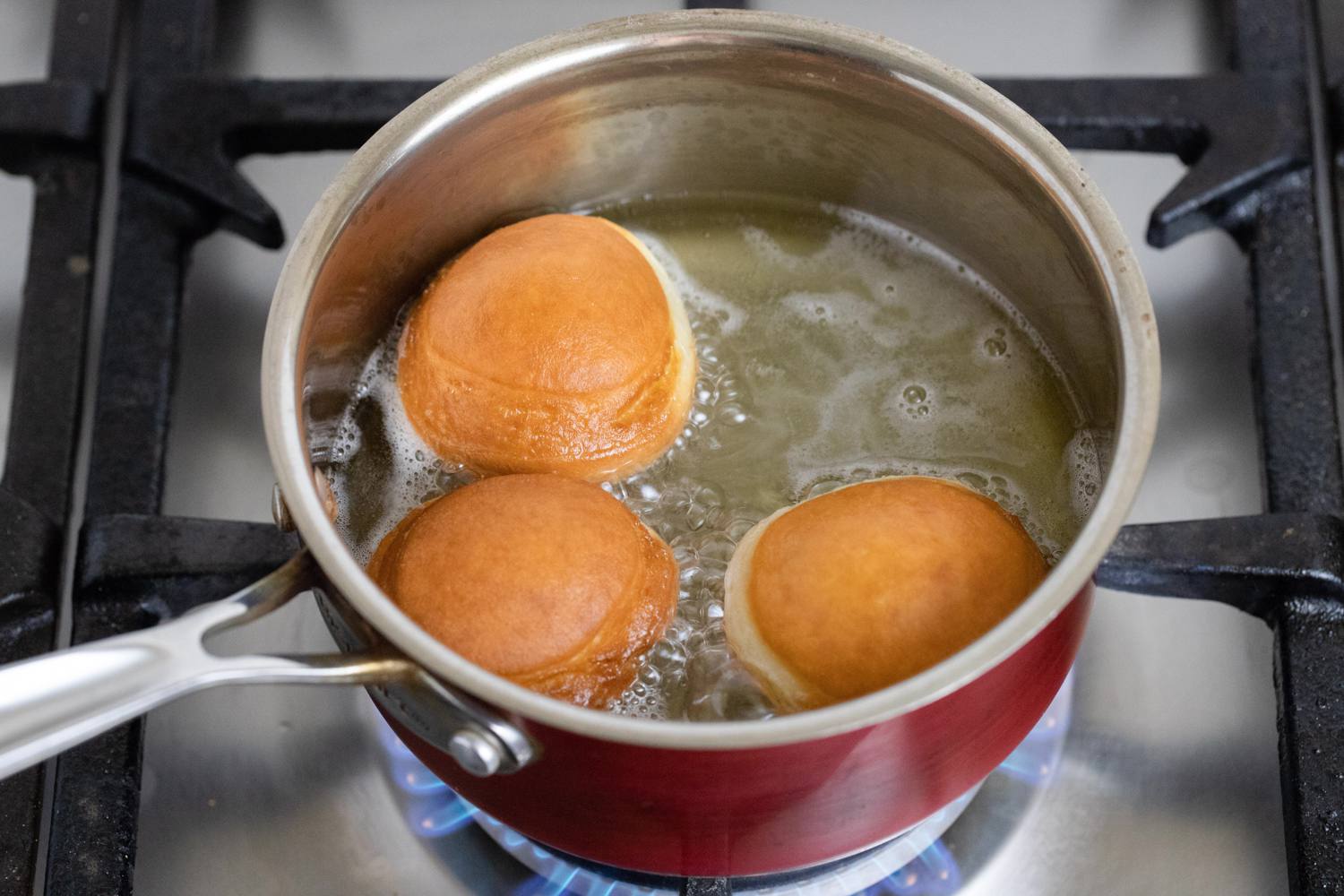 A heavy pot of oil on a stovetop with a thermometer clipped to the side, ready for frying paczki