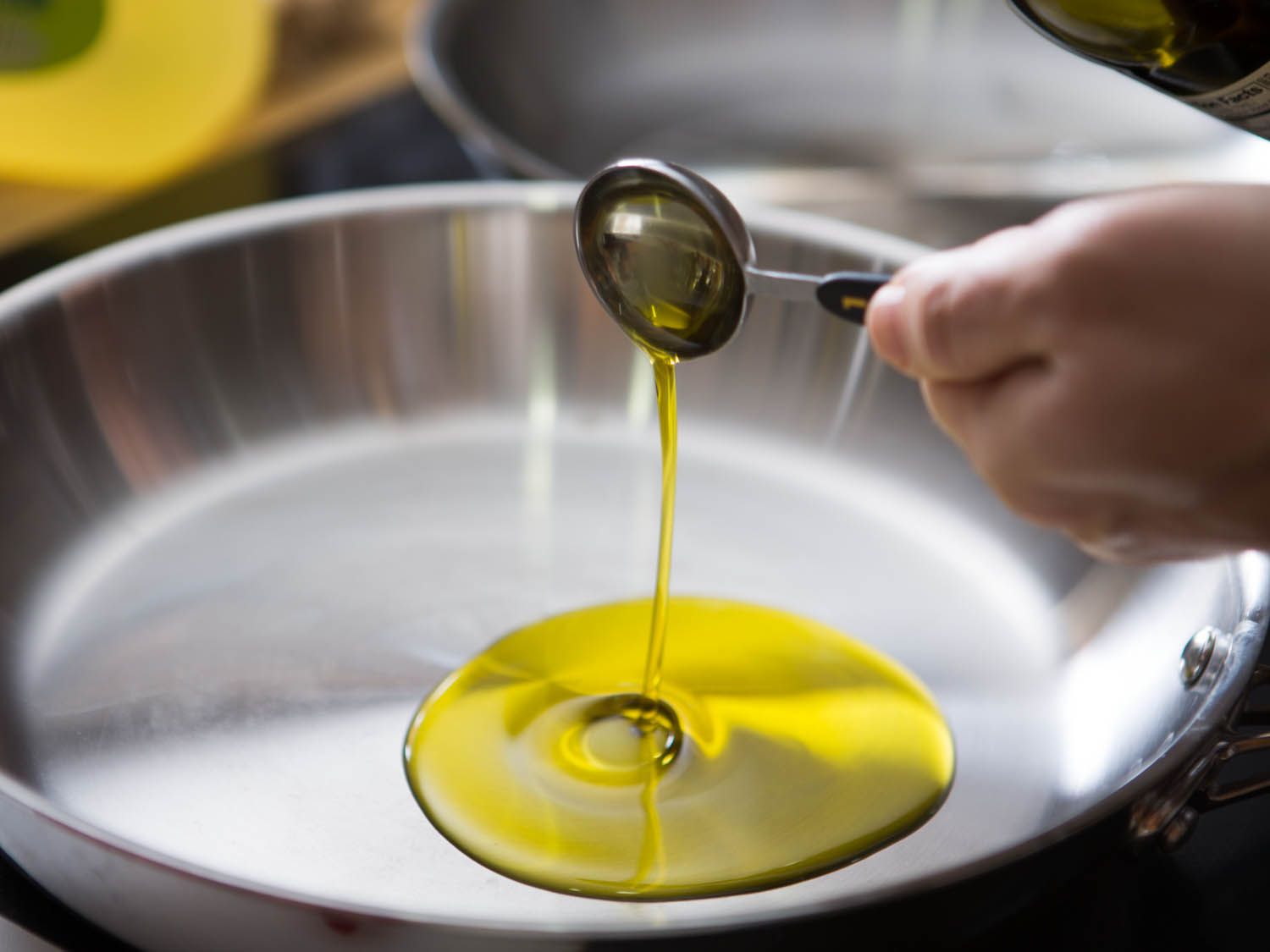 A hot skillet on a stovetop with olive oil shimmering in the bottom, ready for searing fish
