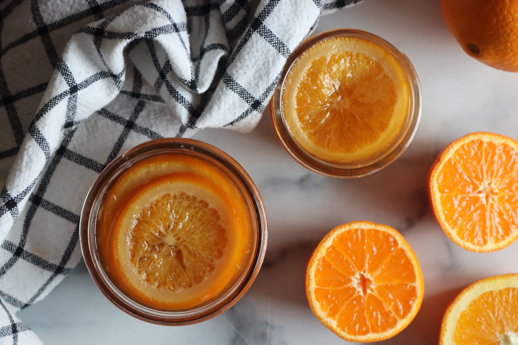 A jar of orange-honey syrup with orange peel nearby