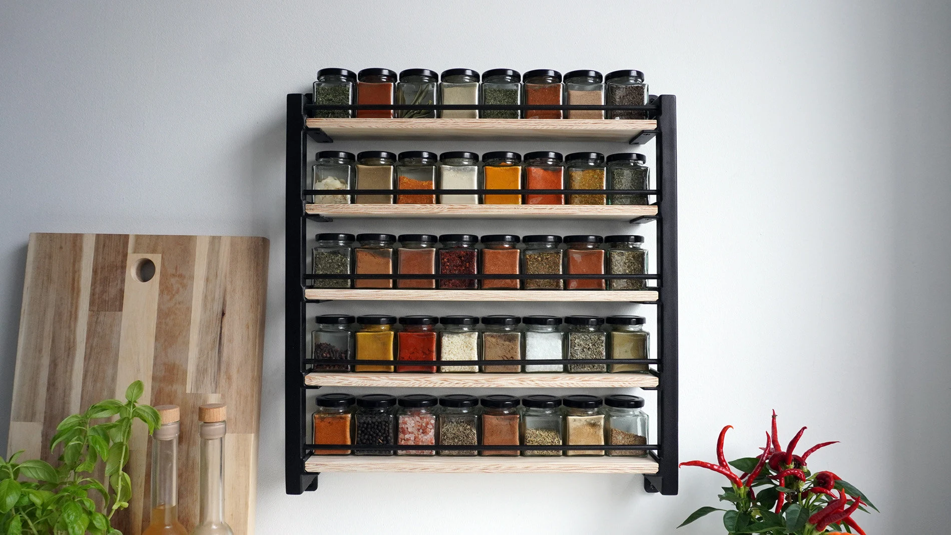 A labeled glass spice jar of pickling spice sitting on a pantry shelf next to other jars, warm indoor lighting