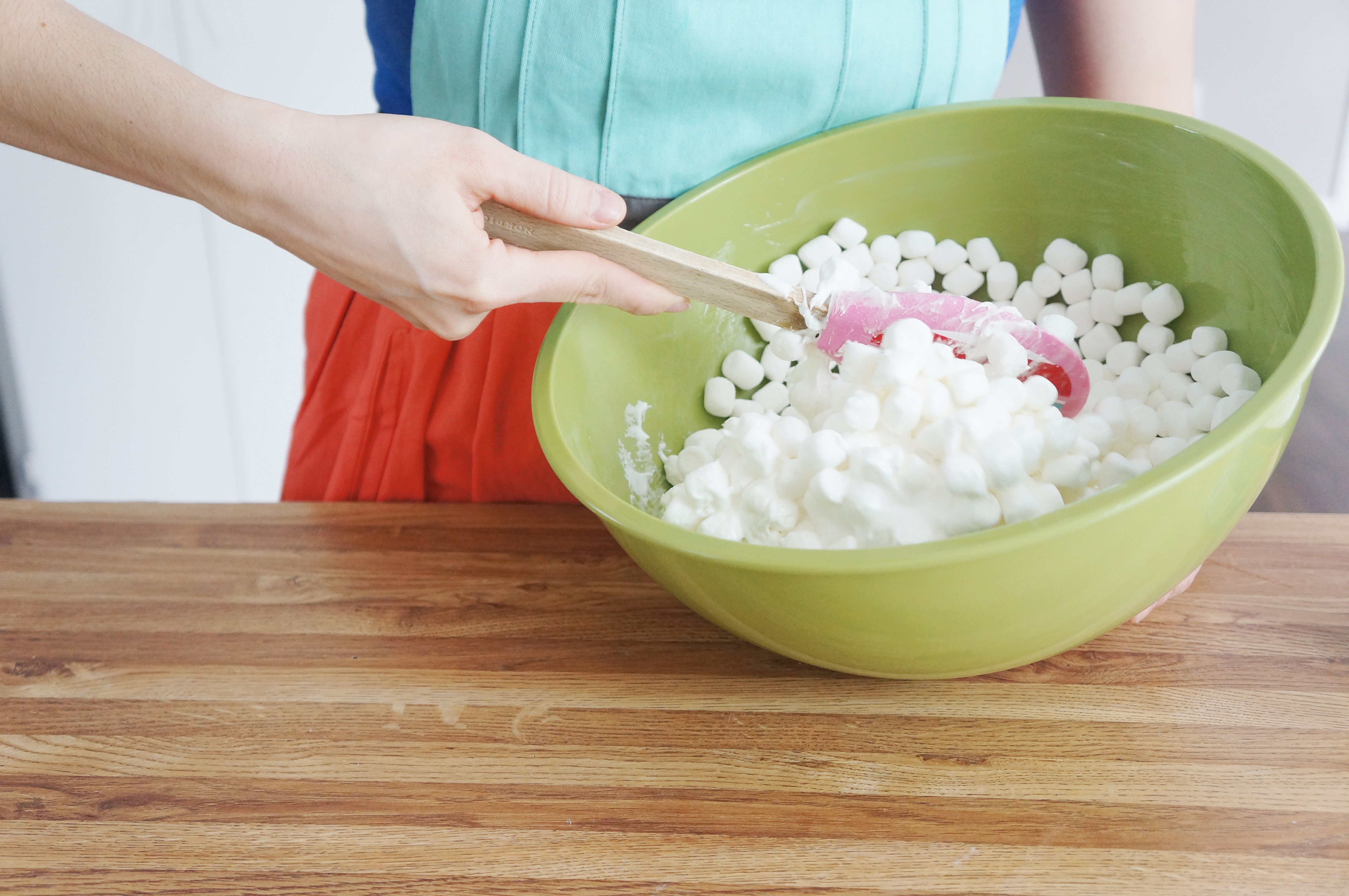 A large bowl of melted marshmallows with a spatula resting inside on a kitchen counter