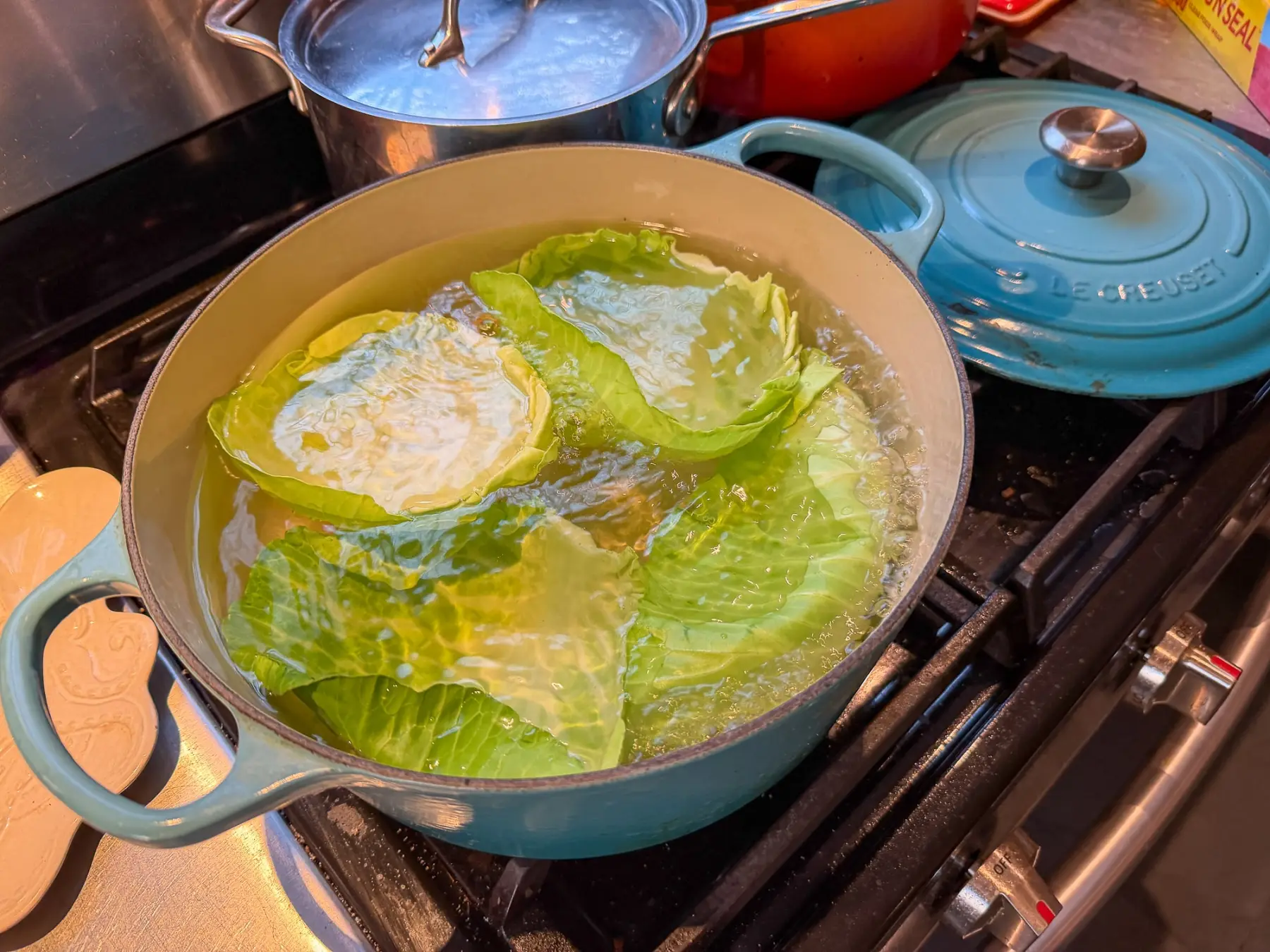 A large pot on the stove simmering with potatoes, corn halves, and sausage coins in a seasoned broth