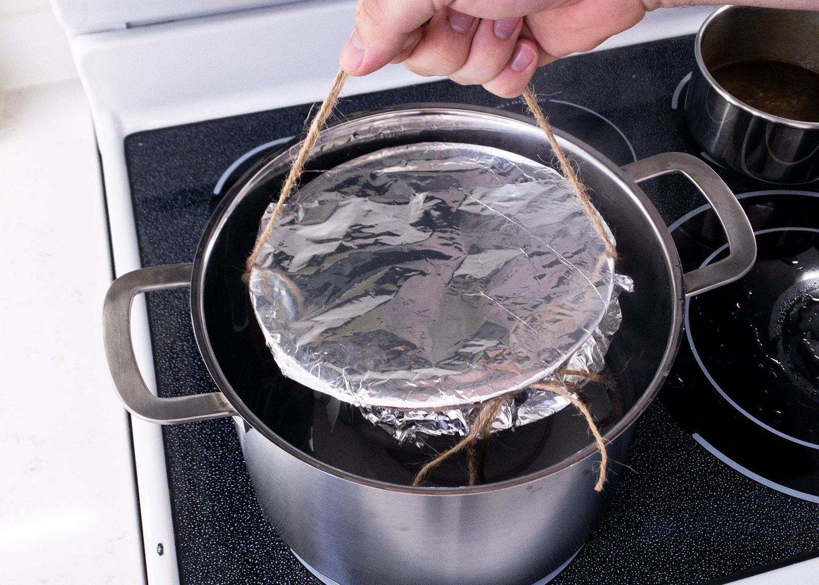 A large pot on the stove with gently simmering water and a trivet inside, ready for steaming a pudding