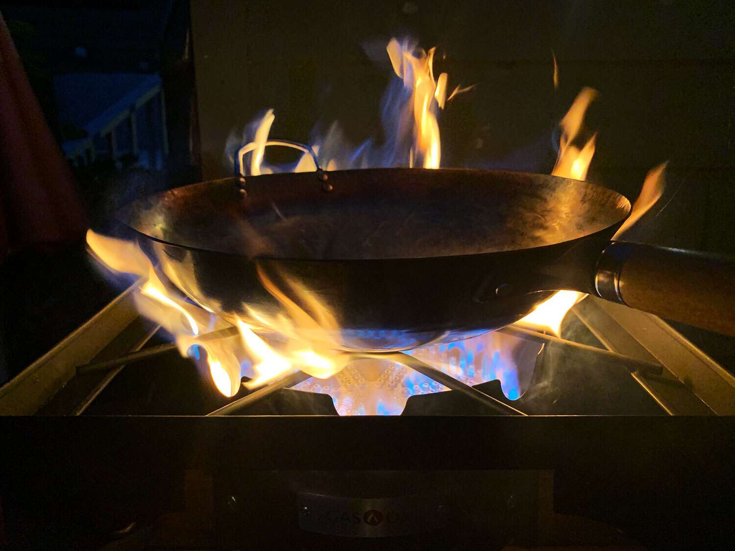 A large wok heating over a gas stove burner