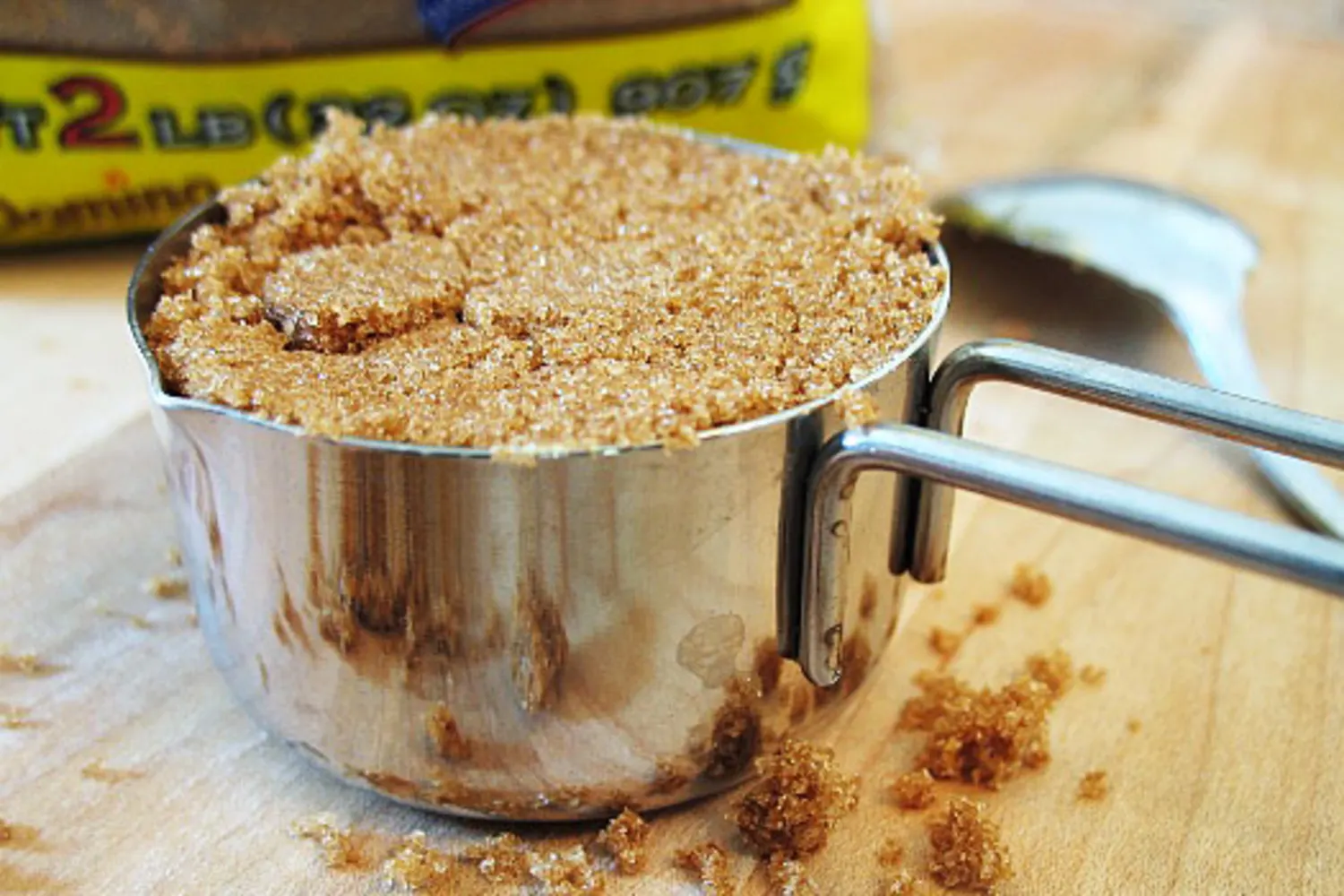A measuring cup filled with packed brown sugar on a kitchen counter next to a small bowl of salt