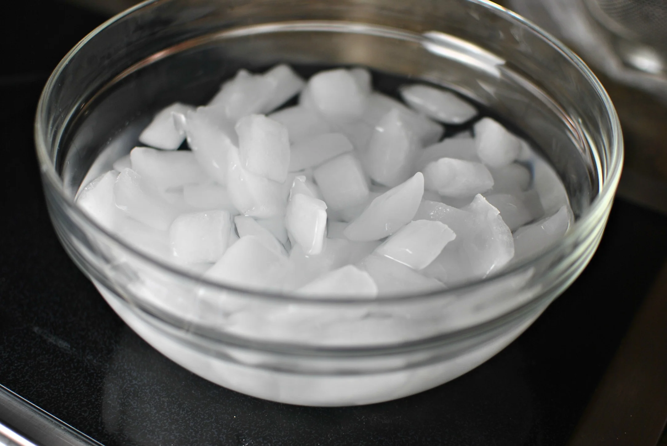 A metal bowl filled with ice water on a kitchen counter, ready for cooling boiled eggs