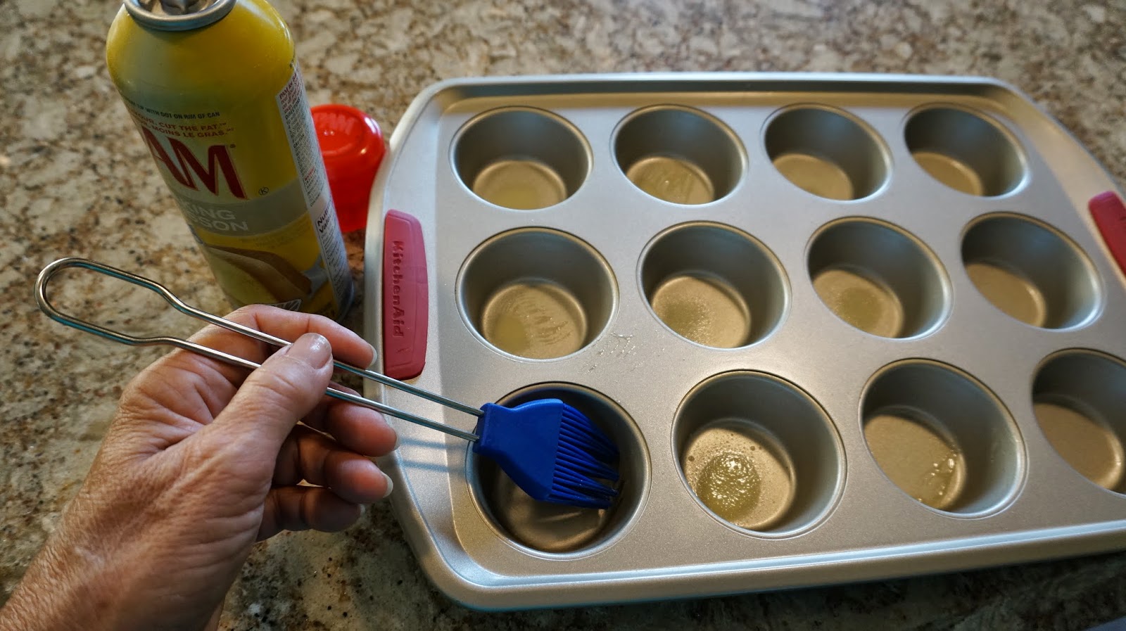 A mini muffin pan being greased on a clean kitchen counter