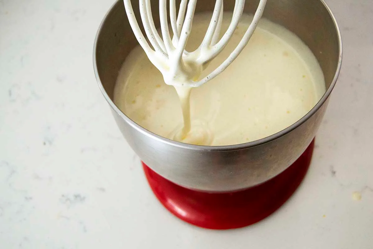 A mixing bowl with eggs and sugar being gently whisked until smooth on a kitchen counter