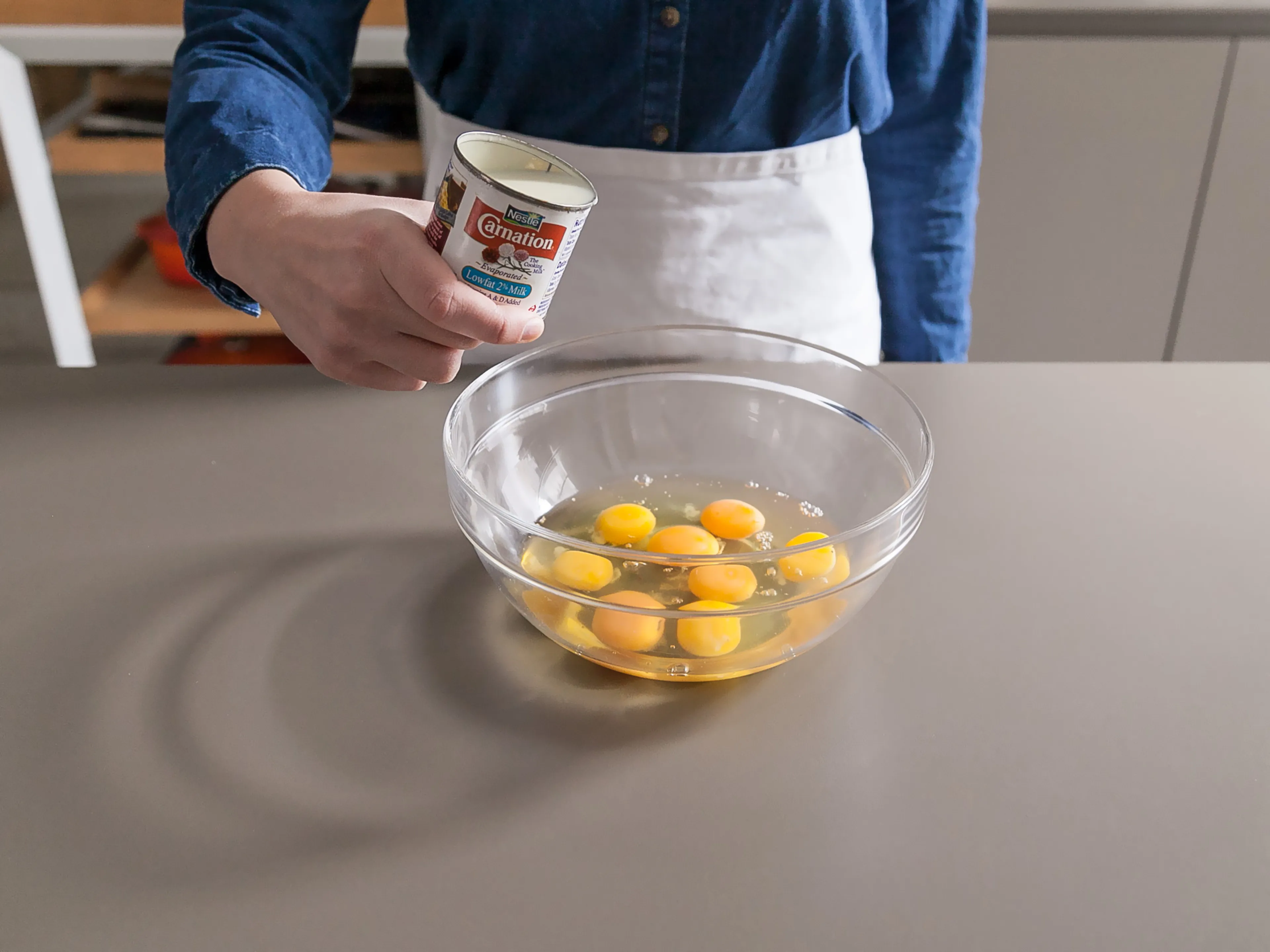 A mixing bowl with evaporated milk and eggs being whisked until smooth on a kitchen counter