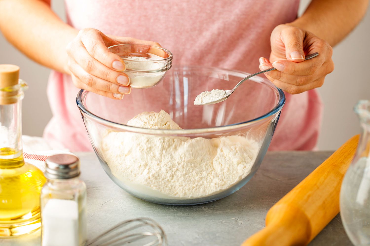 A mixing bowl with flour, baking powder, and salt being whisked together on a kitchen counter