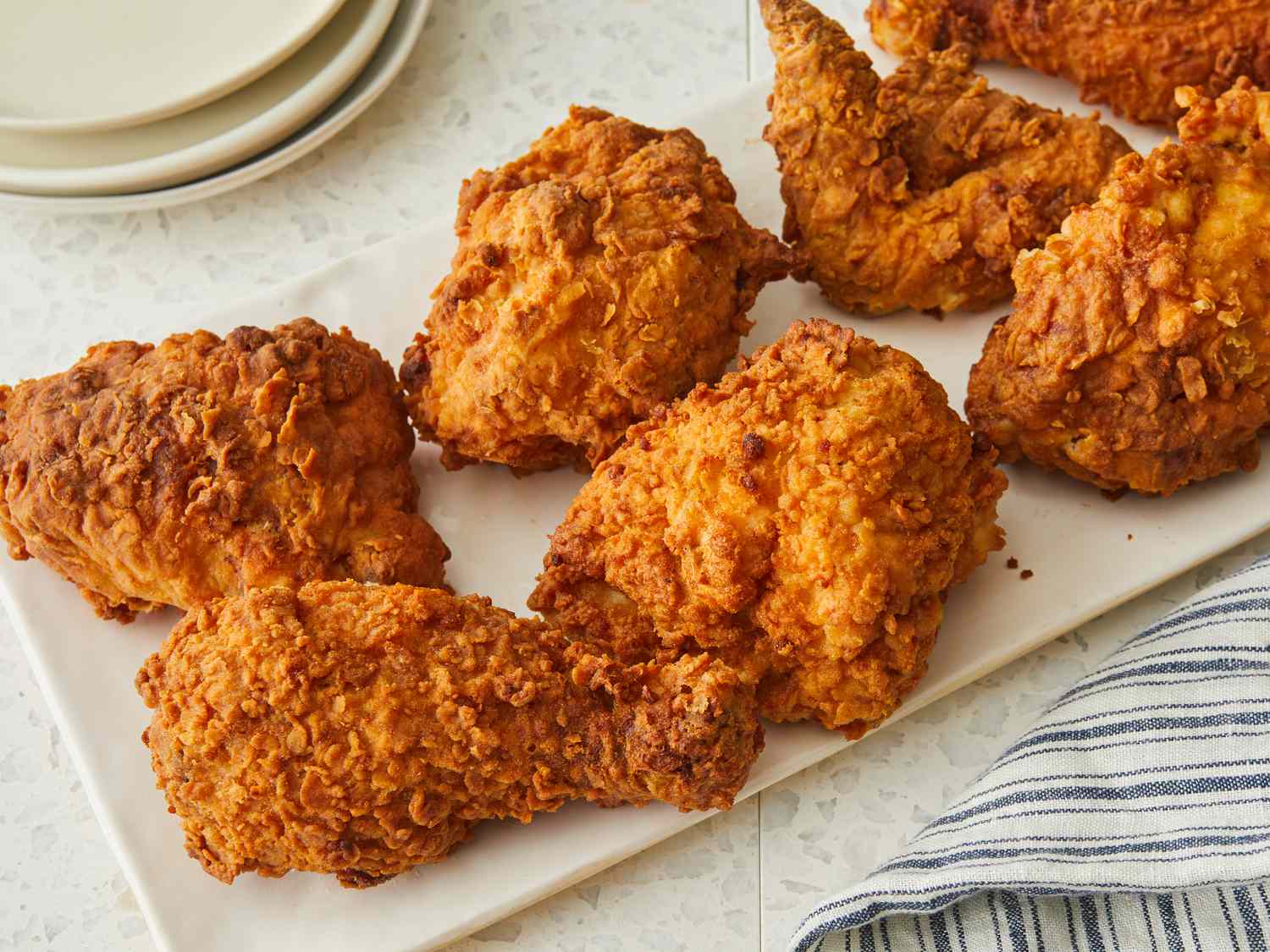 A neat lineup of ingredients for Southern fried chicken on a kitchen counter including chicken pieces, buttermilk, flour, eggs, spices, and a bottle of hot sauce