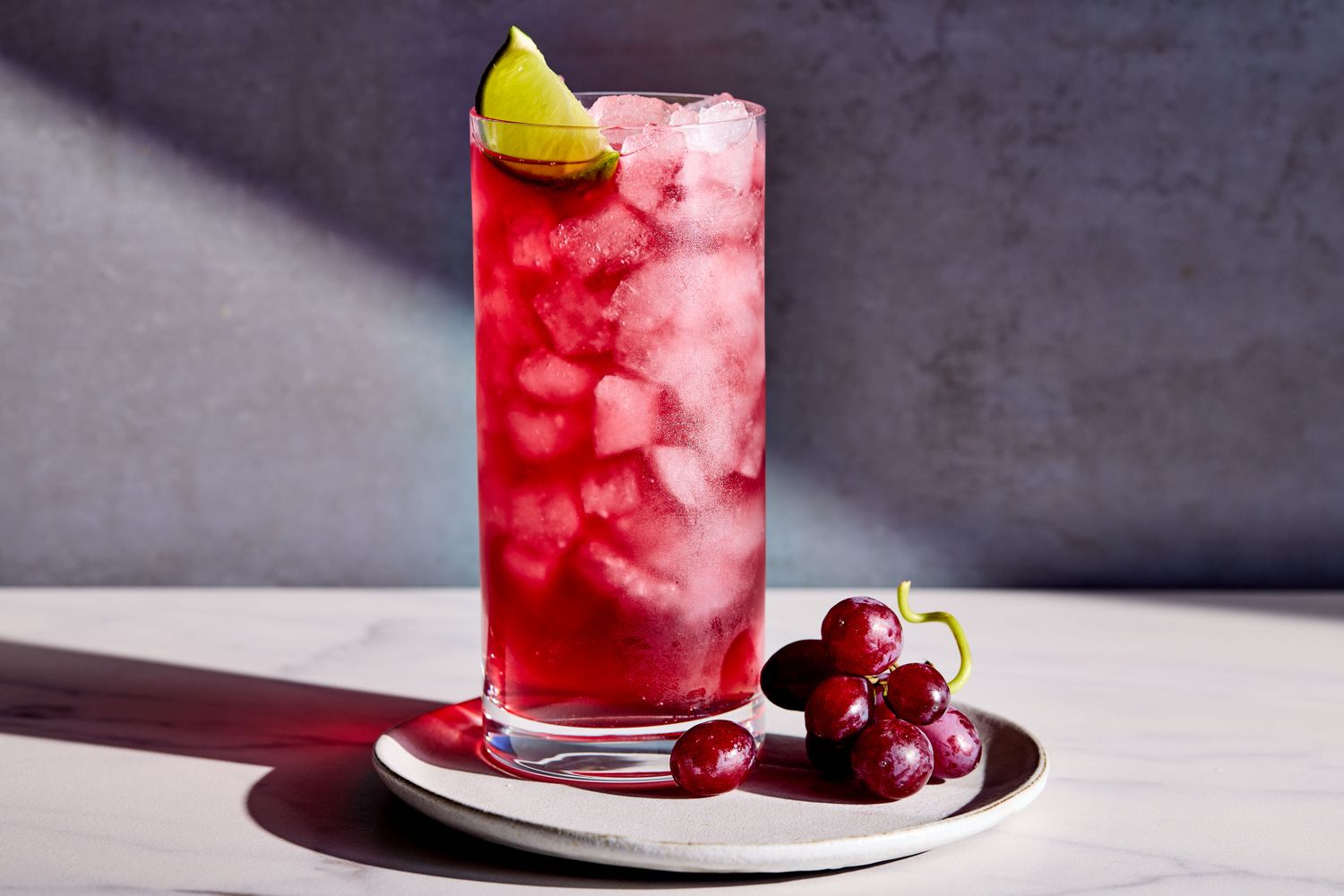 A pale purple Transfusion cocktail in a highball glass filled with ice on a home kitchen counter