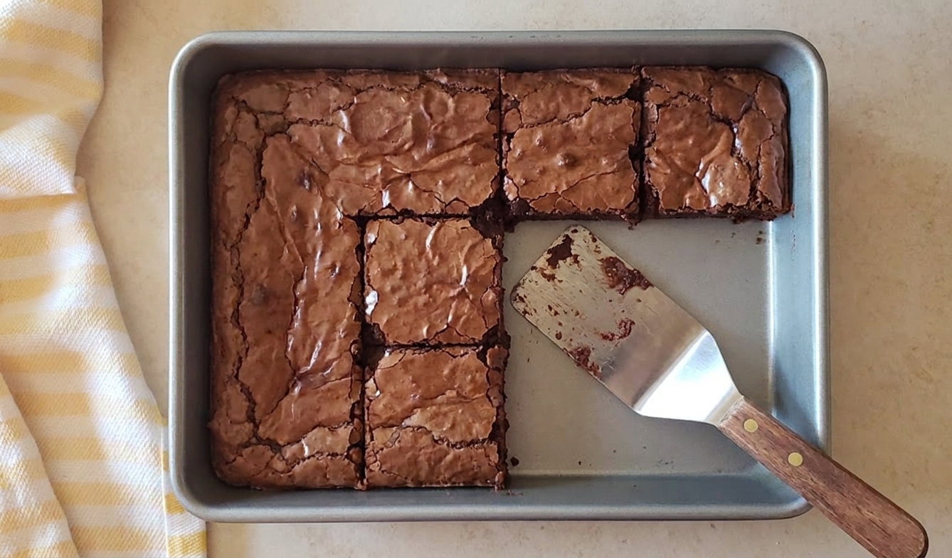 A pan of fudgy gluten free brownies with a crackly top and a few squares cut out