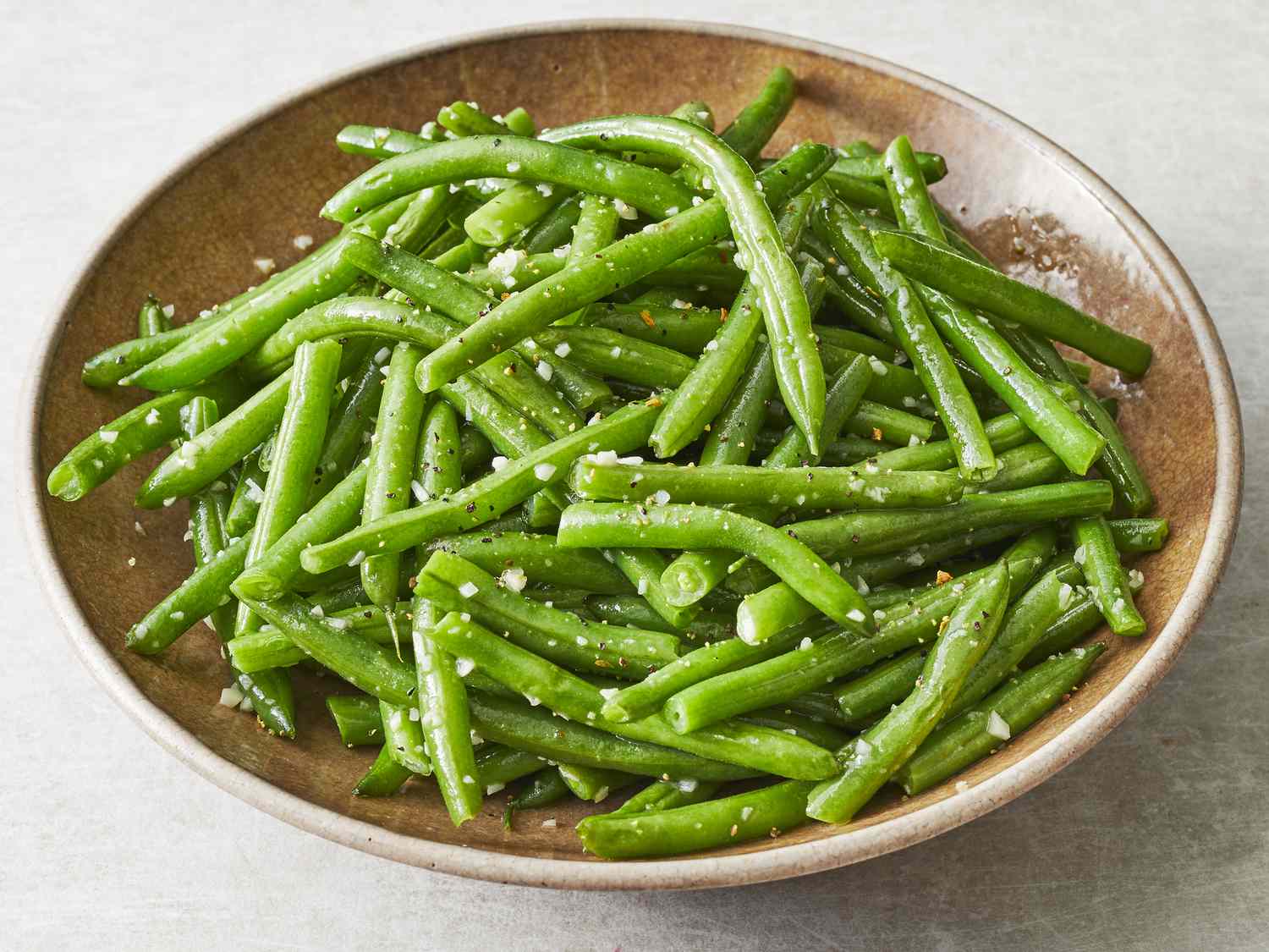 A plate of blistered stir-fried green beans with garlic and sesame seeds, photorealistic restaurant-style food photo