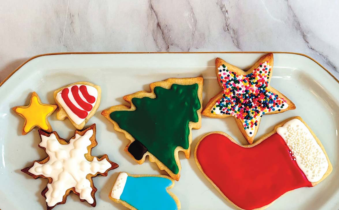 A plate of decorated sugar cookie cutouts with simple icing and sprinkles on a cozy kitchen table with soft natural light