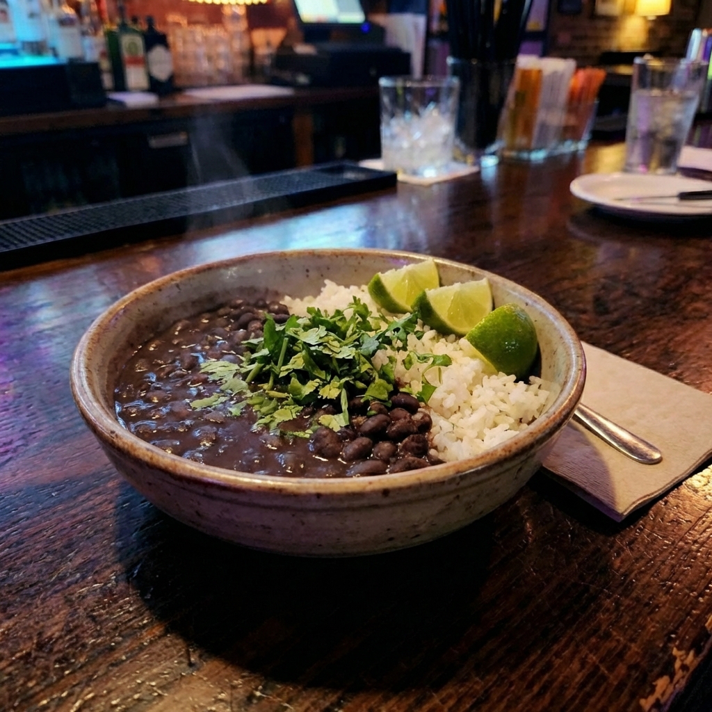 A real photo of a black bean and rice bowl topped with chopped cilantro and lime
