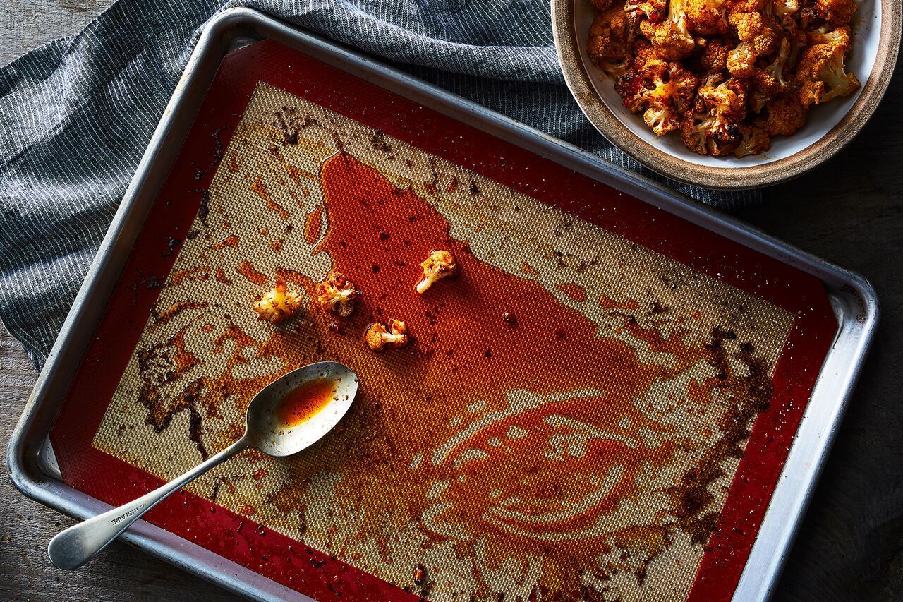 A rimmed baking sheet lined with a silicone mat on a kitchen counter, ready for hot candy to be poured