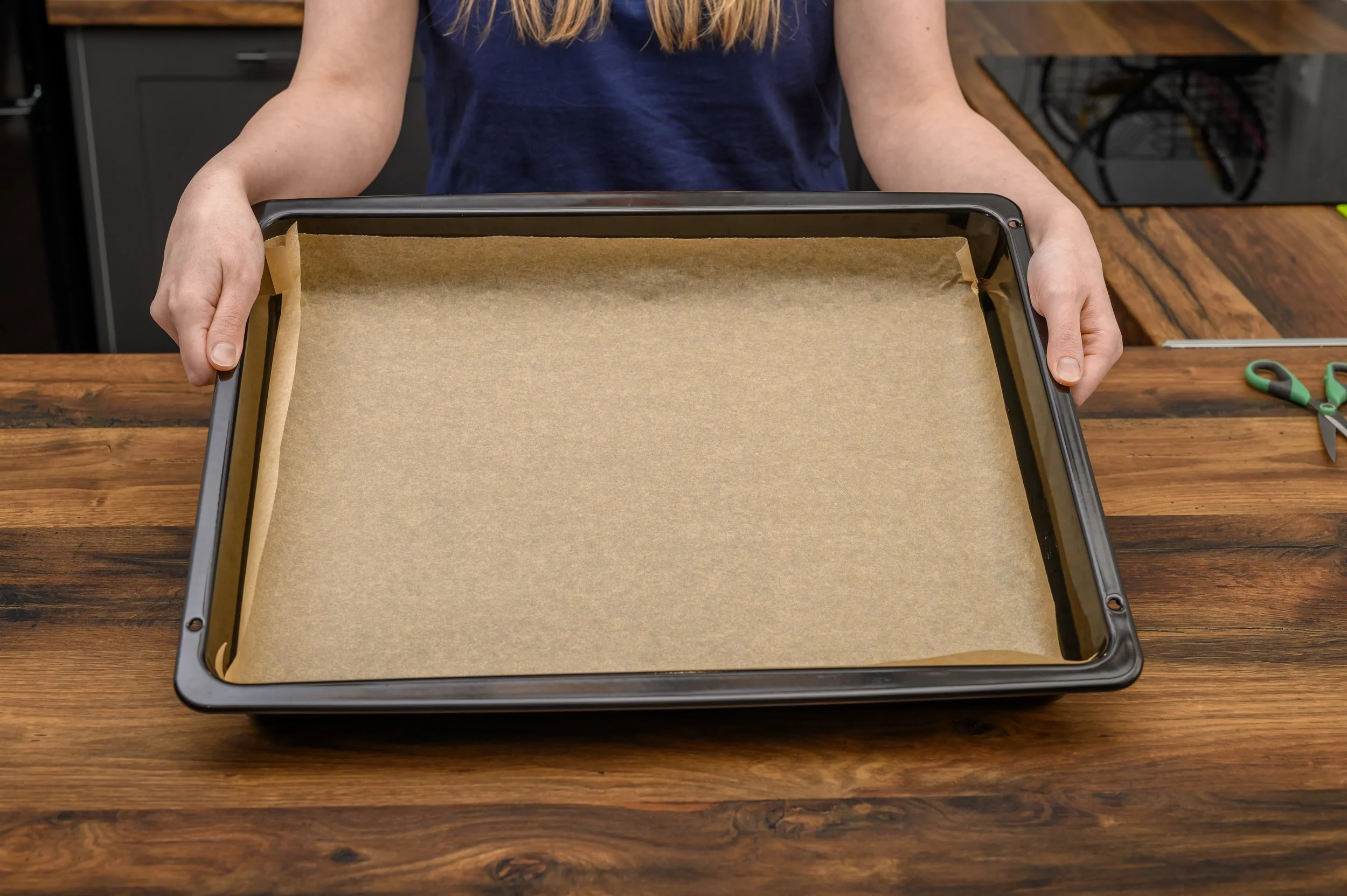 A rimmed baking sheet lined with parchment paper on a kitchen counter ready for dog treats
