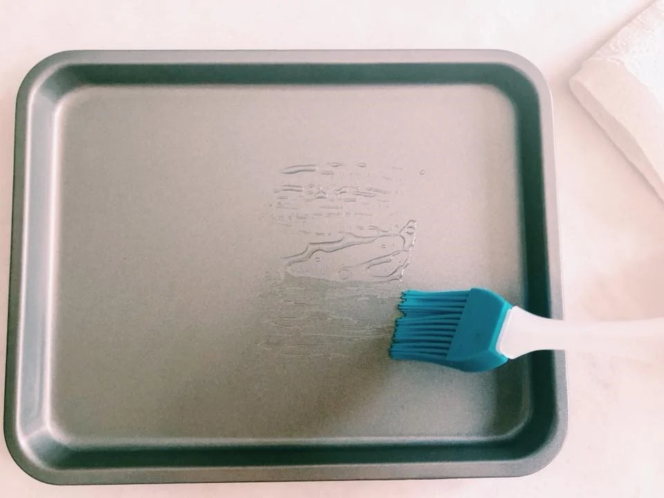 A rimmed sheet pan with a thin layer of oil warming in a preheated oven