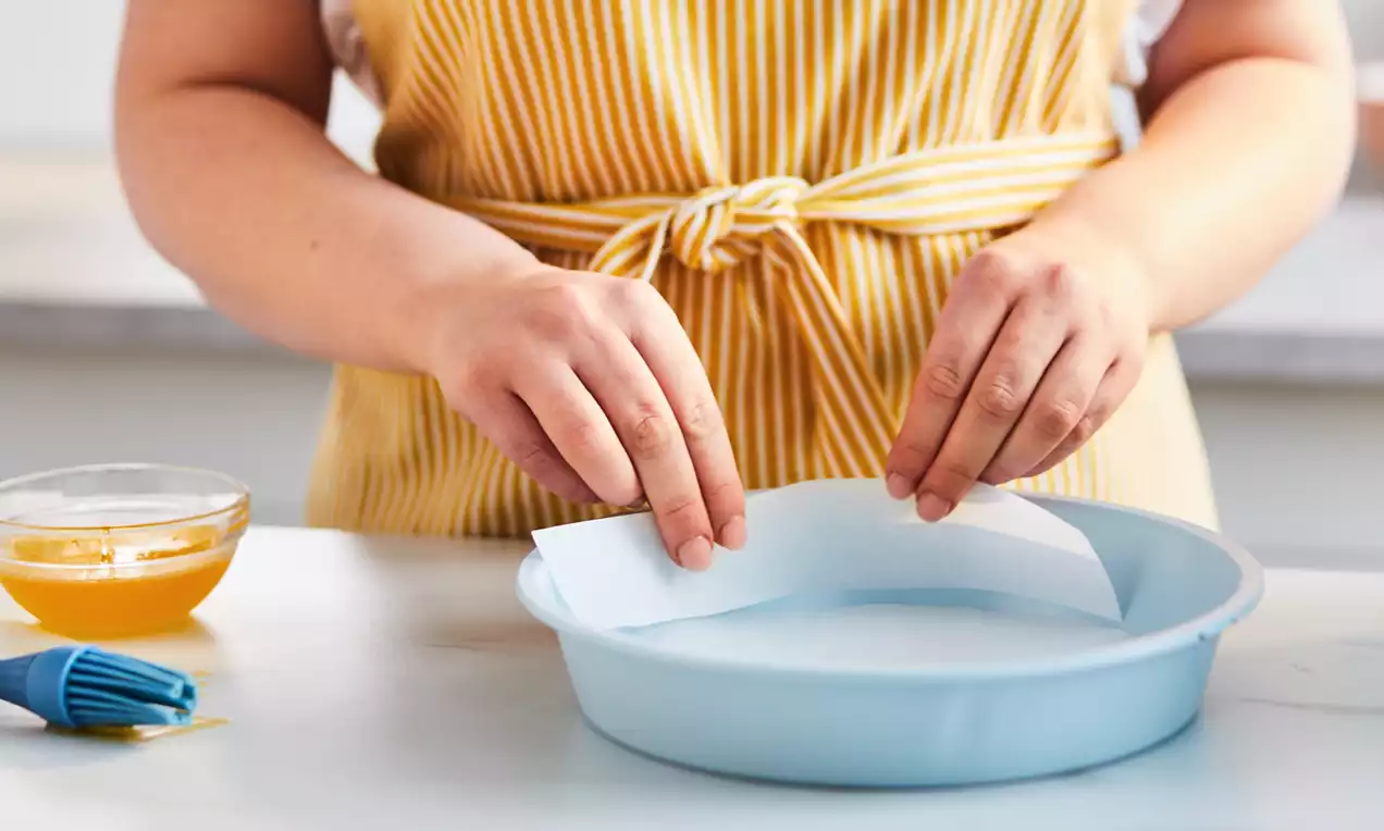 A round cake pan with the bottom lined with parchment paper and brushed generously with melted butter