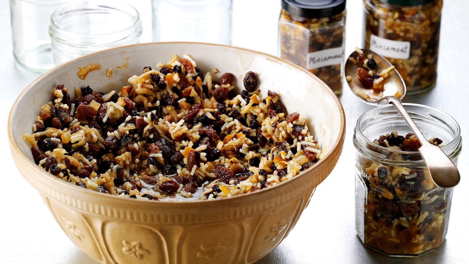 A sealed glass jar of homemade mincemeat sitting on a refrigerator shelf beside butter and eggs