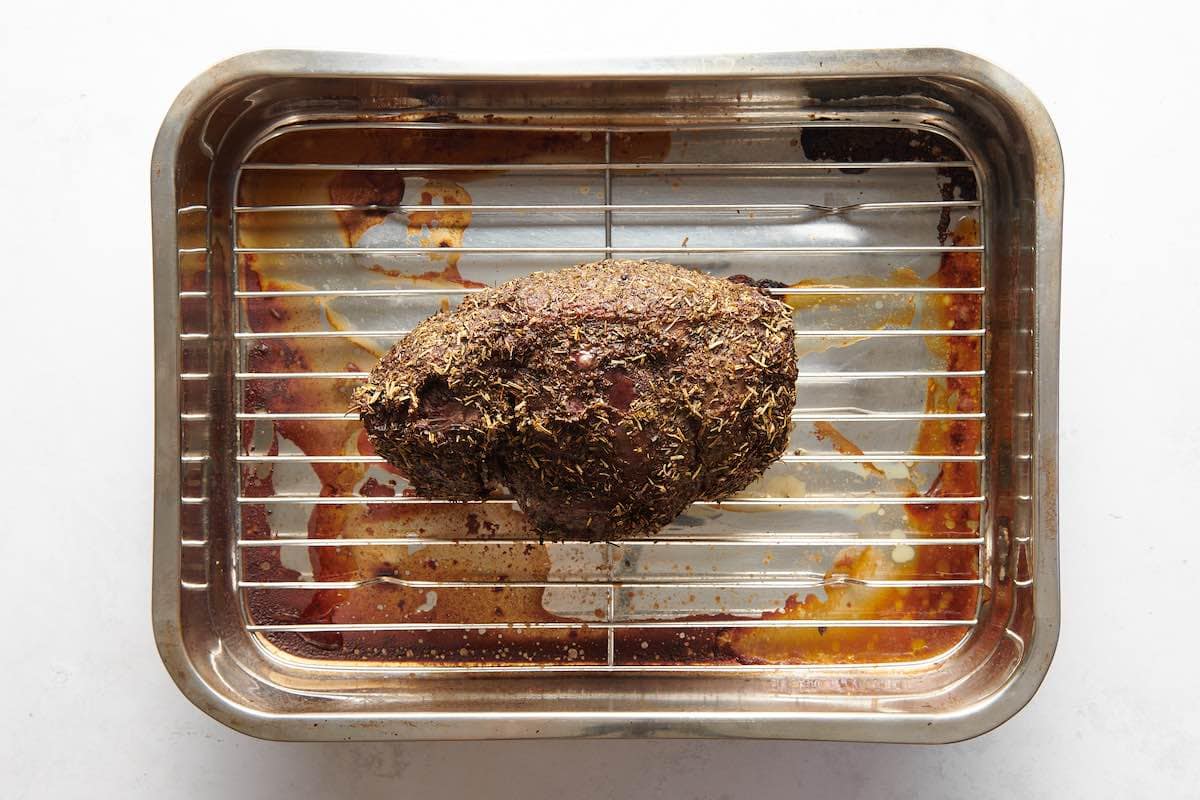 A seasoned top round roast on a wire rack in a roasting pan as it comes out of the oven, real food photography