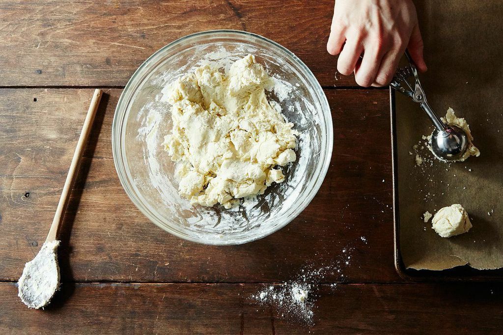 A shaggy, partially mixed bread dough in a large mixing bowl with flour streaks along the sides