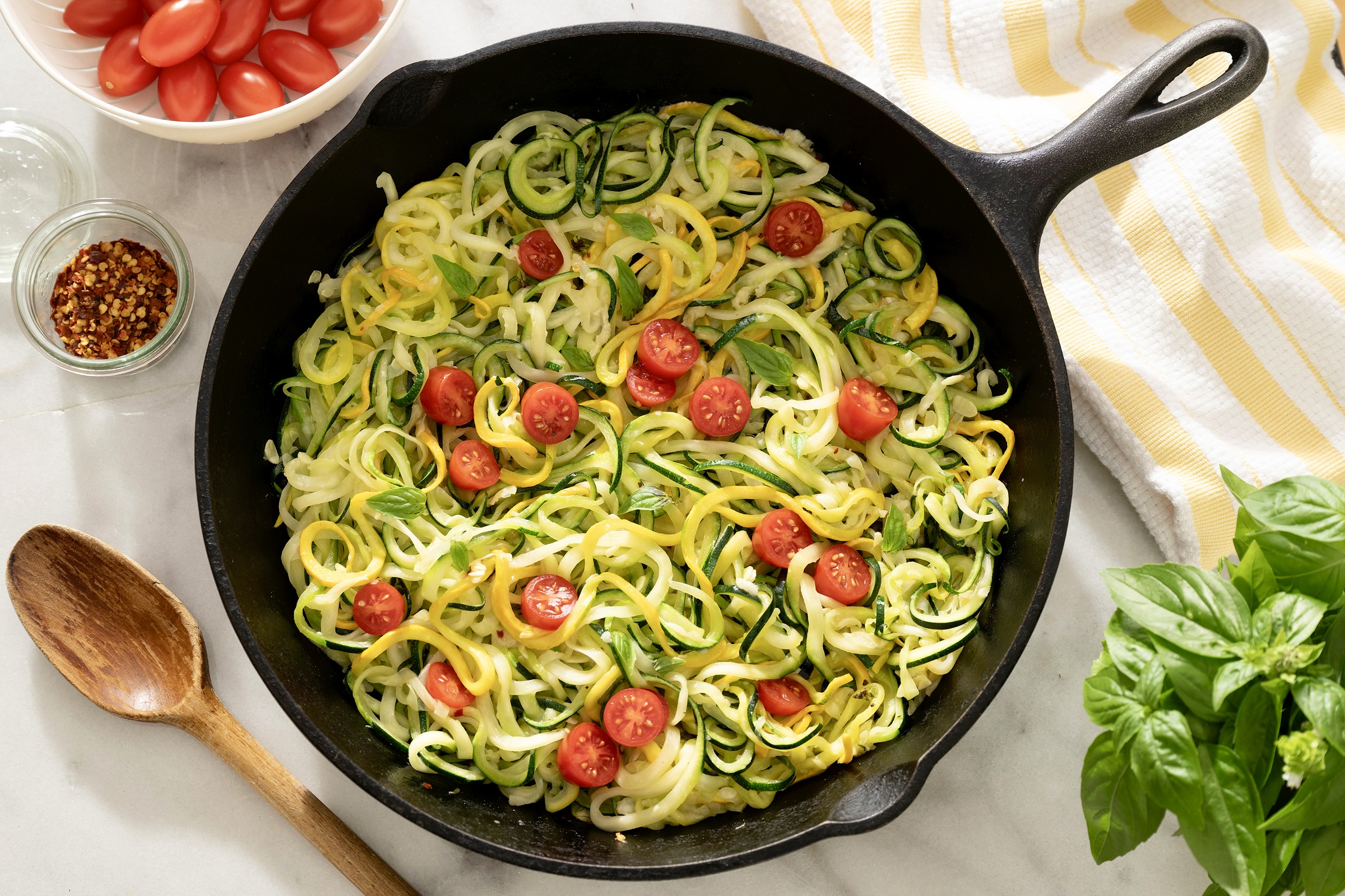 A shallow bowl of garlic Parmesan courgette noodles with flecks of black pepper and lemon zest