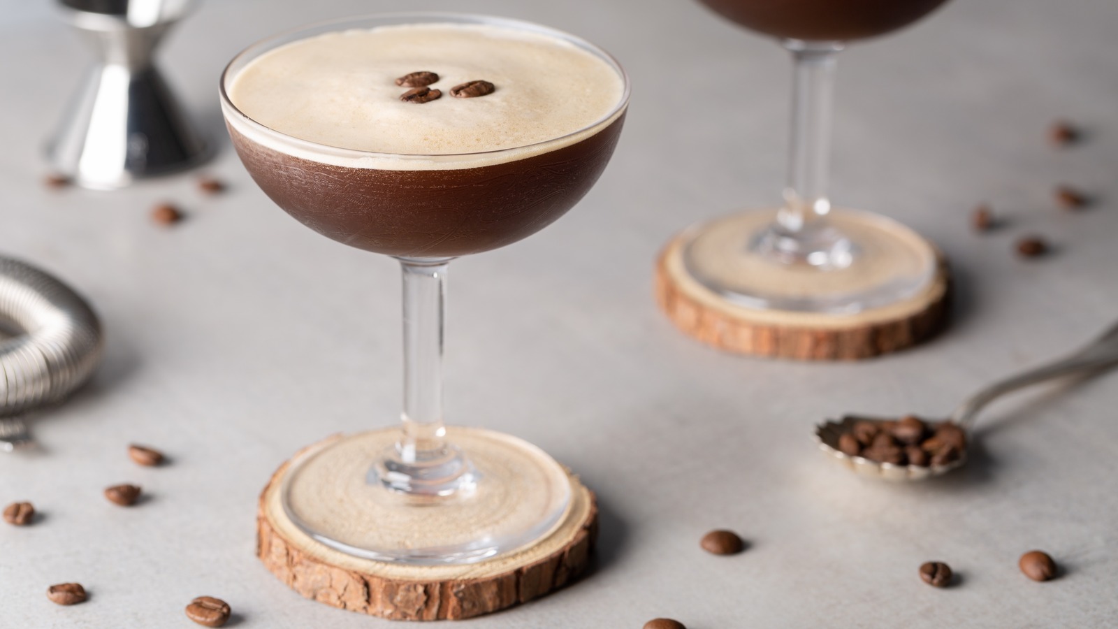 A single espresso martini in a chilled coupe glass with a thick layer of crema-like foam on top, set on a warm kitchen counter with soft natural light