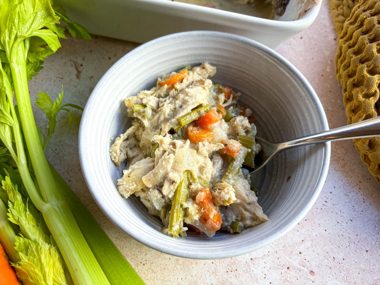 A single slice of chicken pot pie stored in a glass meal prep container on a kitchen counter, showing the creamy filling and flaky crust