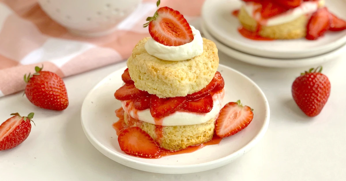A single strawberry shortcake with whipped cream and sliced strawberries on a dessert plate, bright natural light, photorealistic food photography