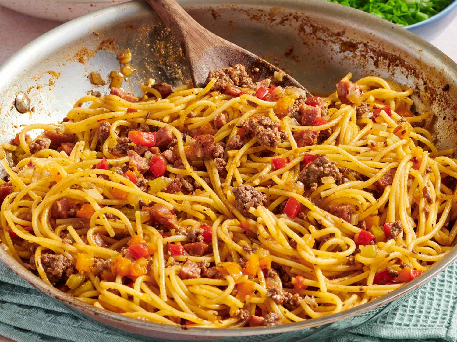 A skillet on a stovetop with dirty spaghetti sauce simmering, showing browned sausage, peppers, and a thick tomato gravy bubbling gently