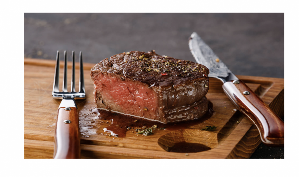 A sliced filet mignon showing a warm pink medium-rare center on a cutting board with pan juices