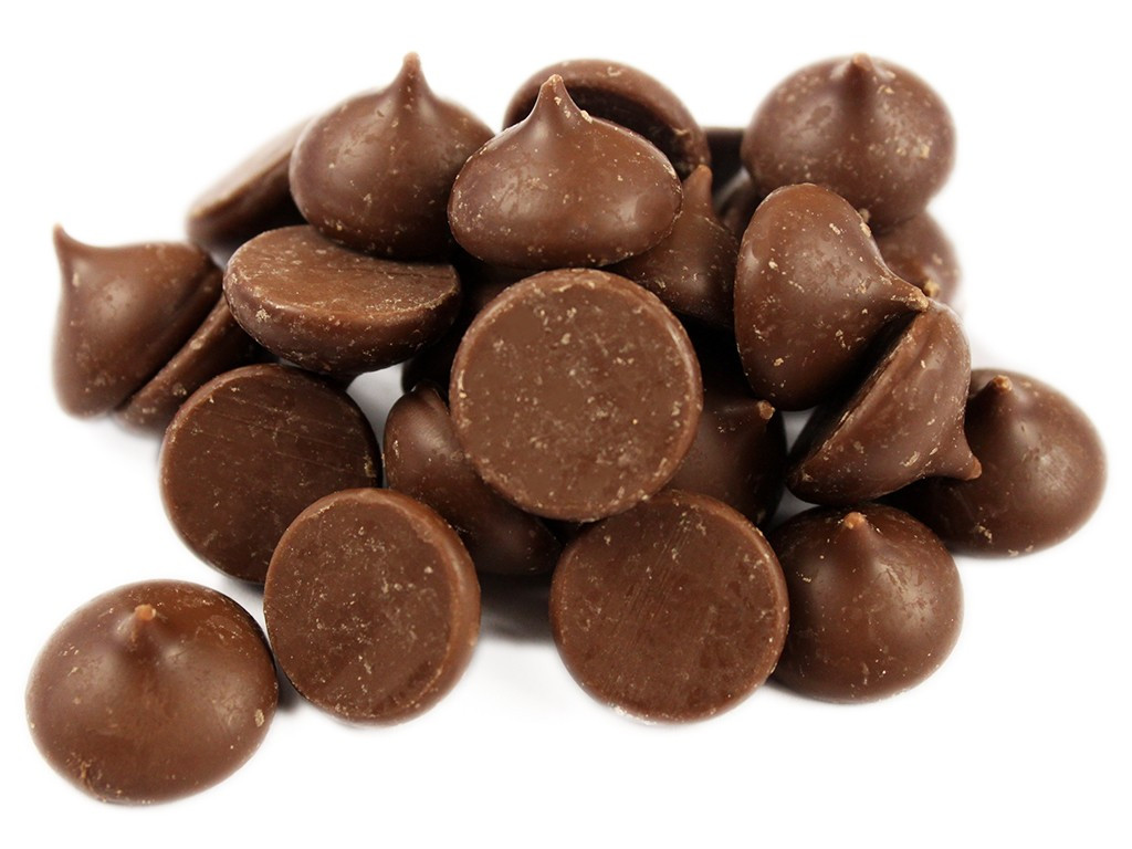 A small bowl filled with unwrapped chocolate kisses on a kitchen counter next to a parchment-lined baking sheet