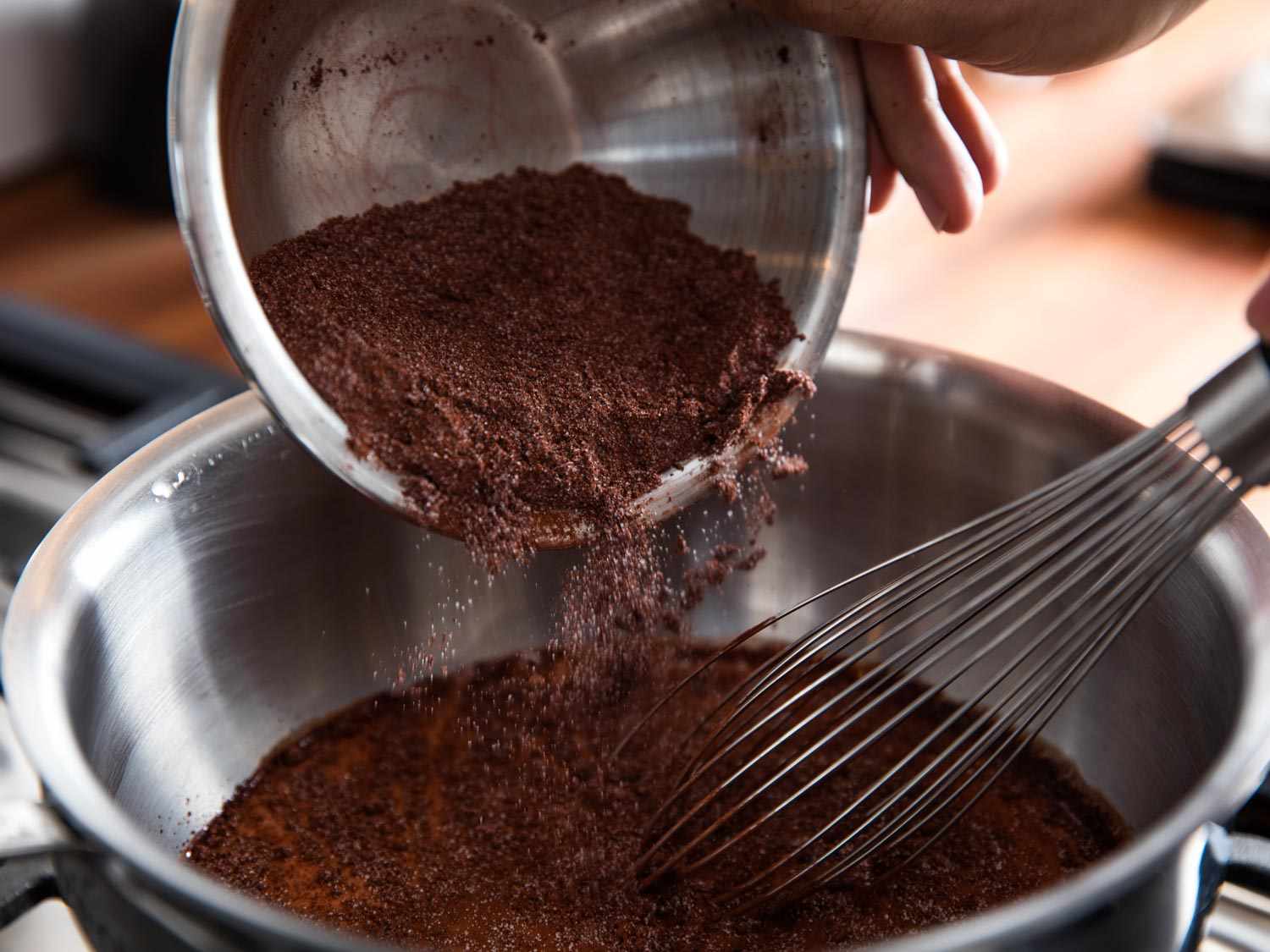 A small bowl of cocoa powder being stirred with hot espresso until smooth and glossy