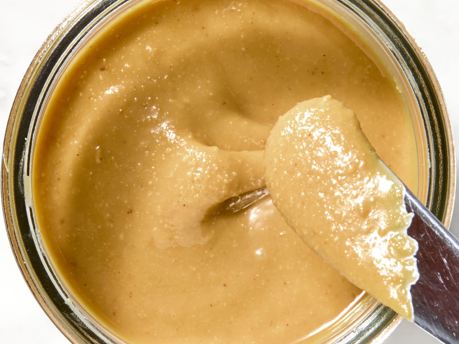 A small bowl of creamy peanut butter warmed until glossy and pourable on a kitchen counter