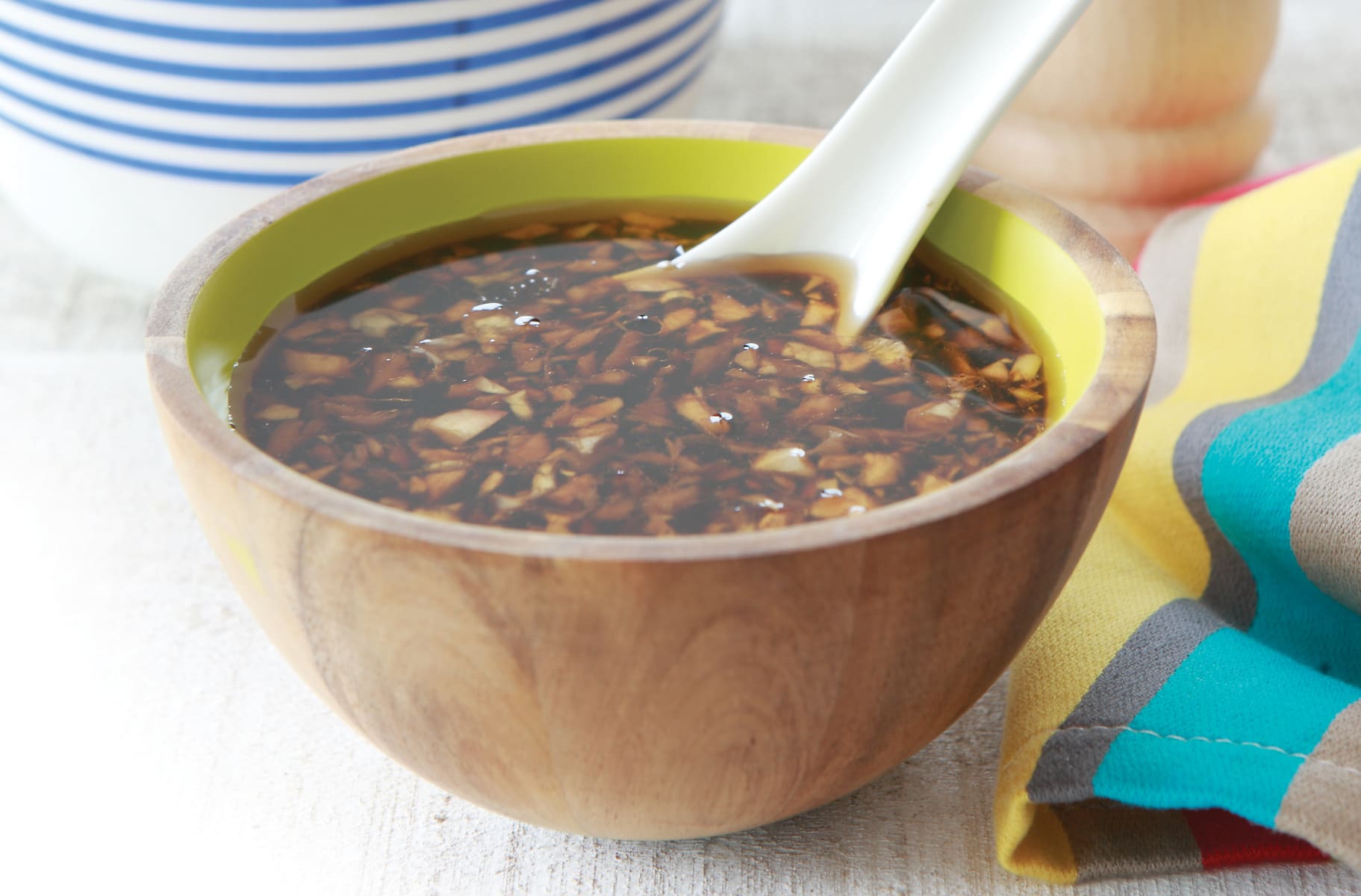 A small bowl of glossy stir-fry sauce with minced garlic and grated ginger on a kitchen counter
