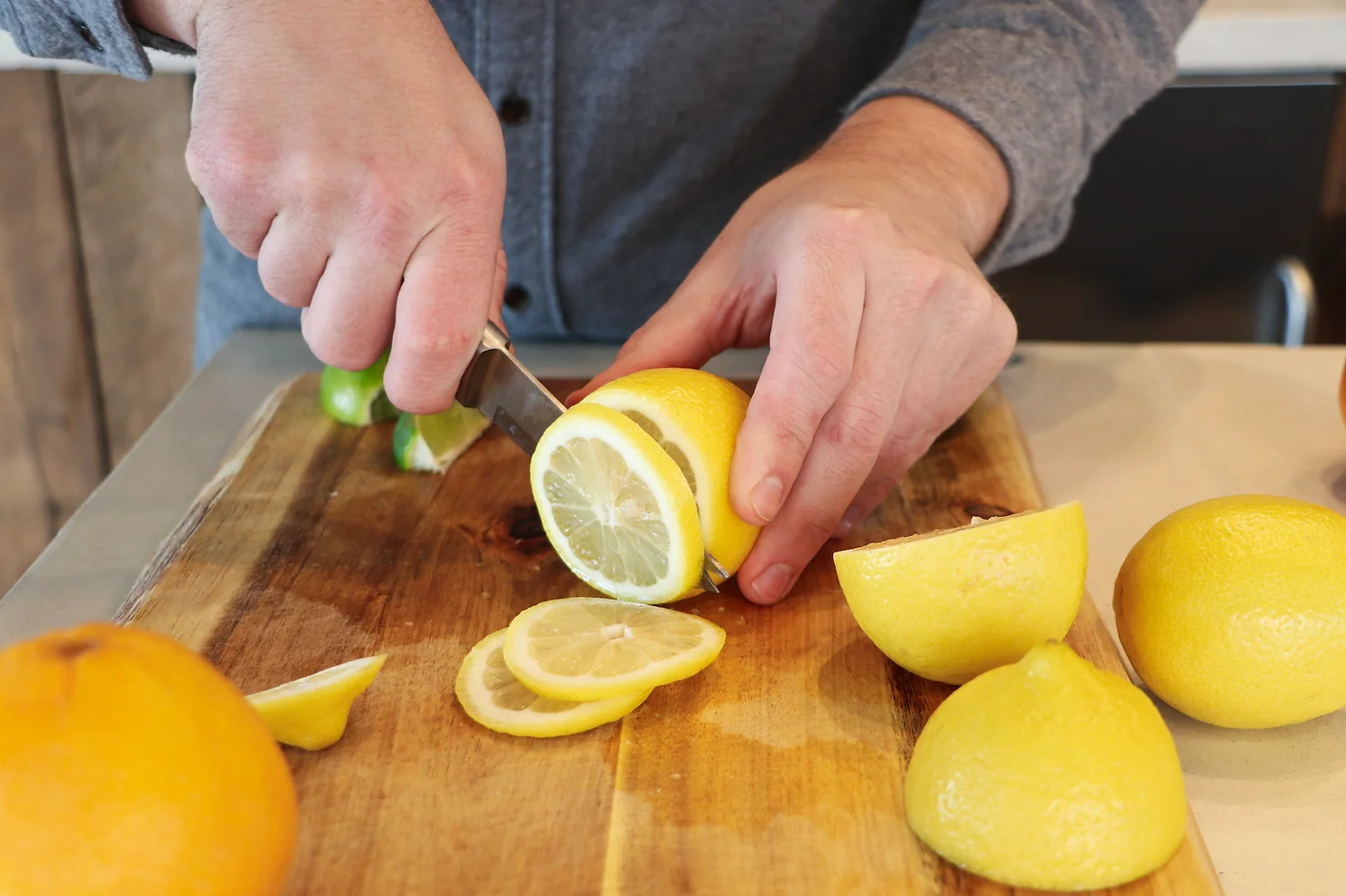 A small cutting board with lemon wheels and a few maraschino cherries prepped for cocktail garnishes on a kitchen counter