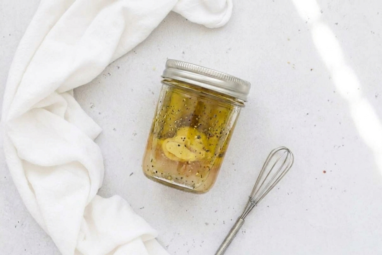 A small jar of Dijon vinaigrette with a lid, ready to shake and pour